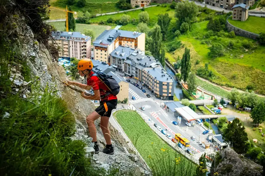 Adolescente escalando una vía ferrata expuesta sobre Andorra la Vella