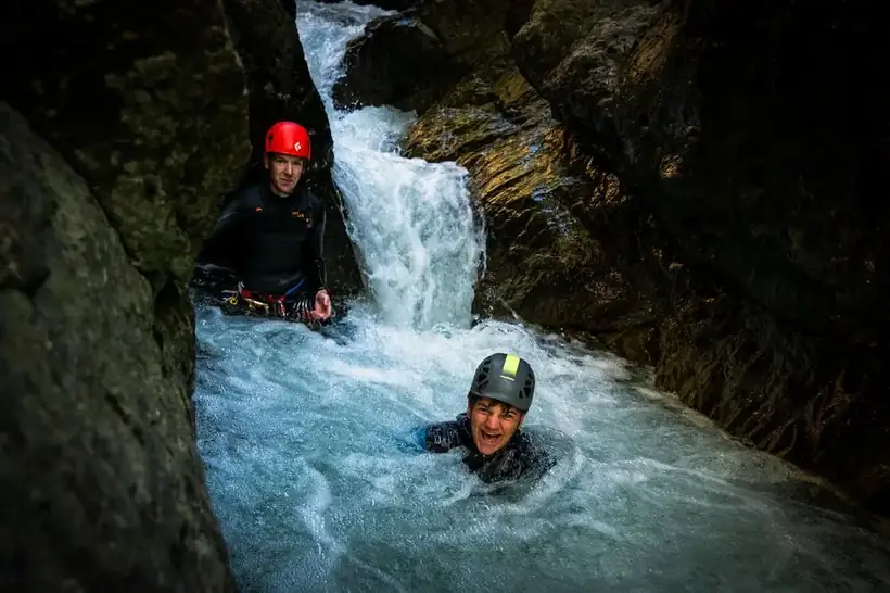 Twee mensen lachend in een canyon-poel na een sprong